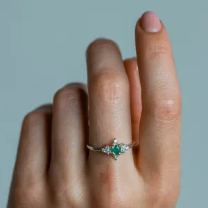 Gold emerald ring with diamonds worn on a finger