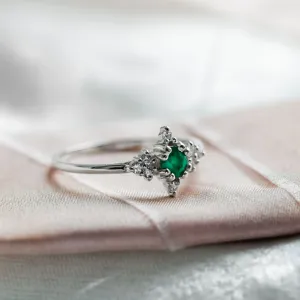 Angled view of a gold emerald ring with diamonds