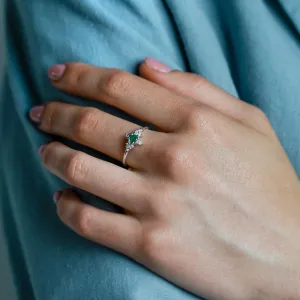 Angled view of the gold emerald ring with diamonds worn on the hand