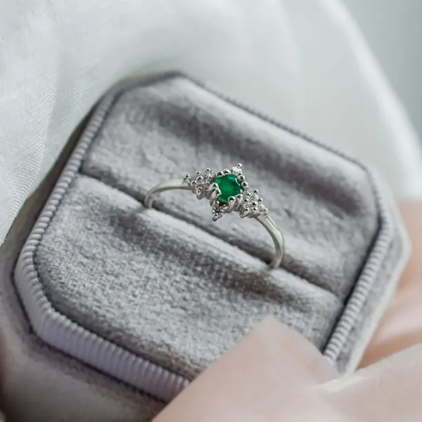 Gold emerald ring with diamonds shown from an angled view