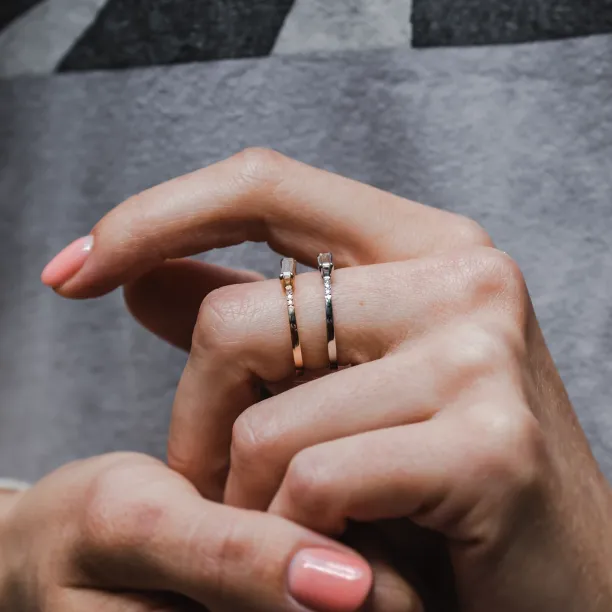 CASSIA engagement ring held beside another ring between fingers
