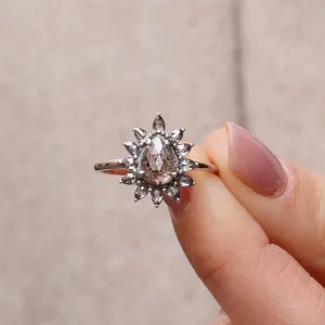 Prsten GIRASOLO se salt'n'pepper diamanty ve tvaru květiny držený mezi prsty
