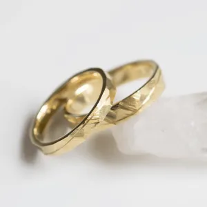 Close-up of LIDO yellow gold wedding rings with hammered surface and line