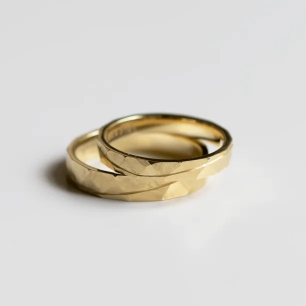 Angled view of overlapping gold wedding rings with hammered surface
