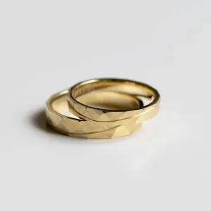 Angled view of overlapping gold wedding rings with hammered surface