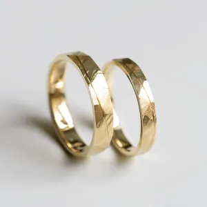 Angled pair of gold wedding rings with hammered surface and line