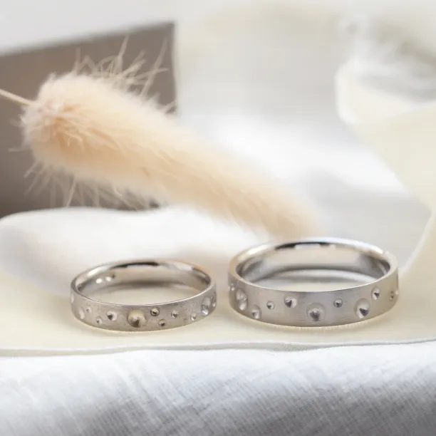 Pair of SELENE space moon wedding bands with varied crater-like perforations