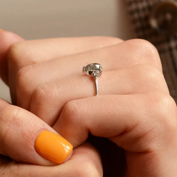 Boční detail zlatého prstenu JACOBELLA s pear salt'n'pepper diamanty drženého v ruce
