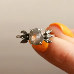 Detail prstenu GIUSTINA se salt'n'pepper diamanty drženého mezi prsty