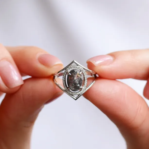 Zlatý prsten MARGHERITA s oválným salt and pepper diamantem držený mezi prsty