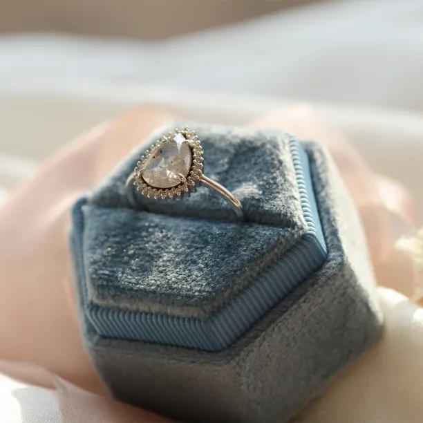 Detailní šikmý pohled na zlatý prsten NOEMI s hruškovitě vybroušeným salt and pepper diamantem a halo efektem z postranních diamantů