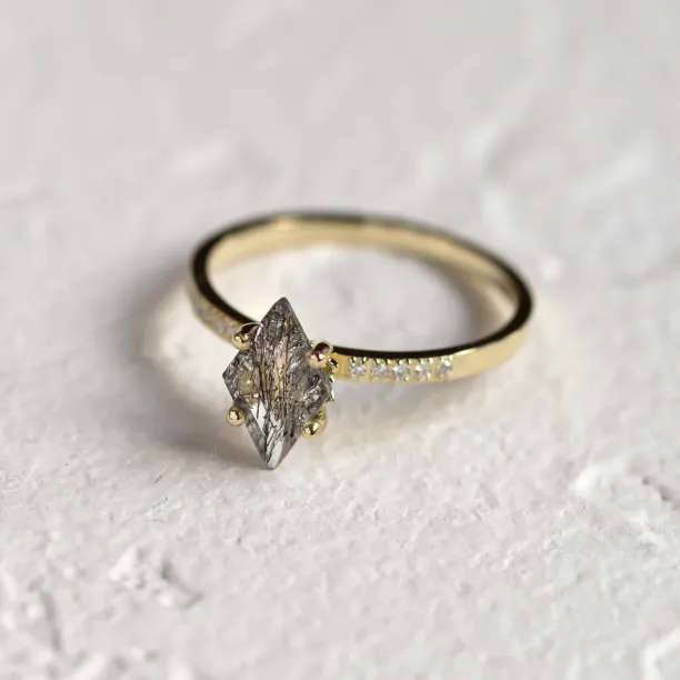 Angled view of ESTER gold ring with kite rutilated quartz and diamond-set band