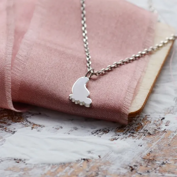 Detailní pohled na zlatý přívěsek ve tvaru dětské nohy BABY