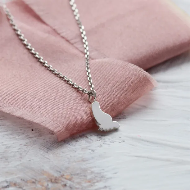 Detailní šikmý pohled na zlatý přívěsek ve tvaru dětské nohy BABY