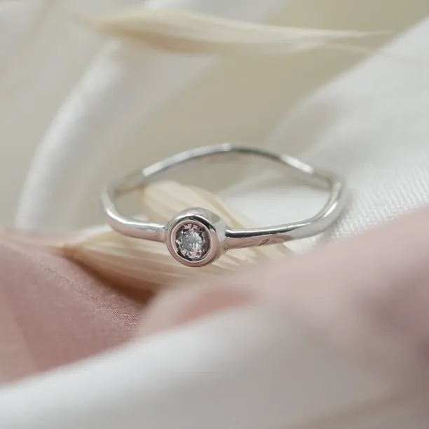 Close-up of the NOLLAIG engagement ring and bezel-set diamond