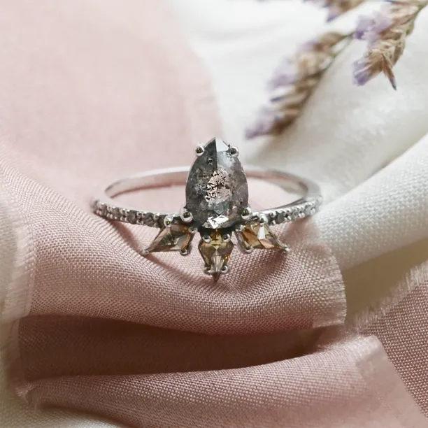 Close-up of the CROWNIA gold ring with a pear-shaped salt-and-pepper diamond and fancy diamonds