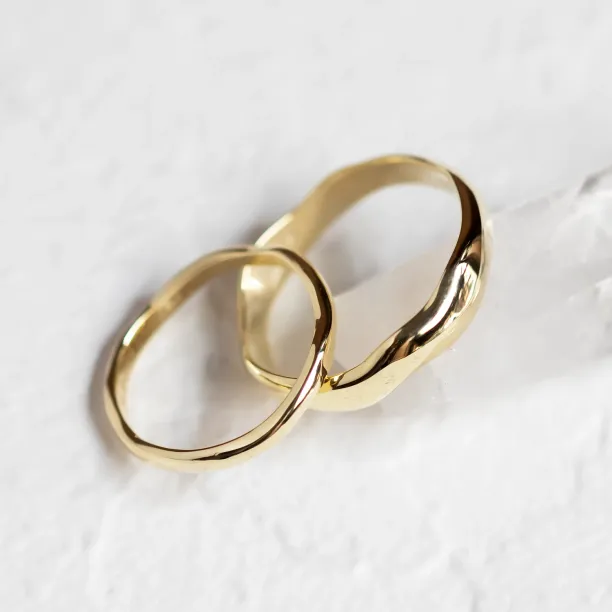 Angled close-up of the LUANA pair of irregular gold wedding rings