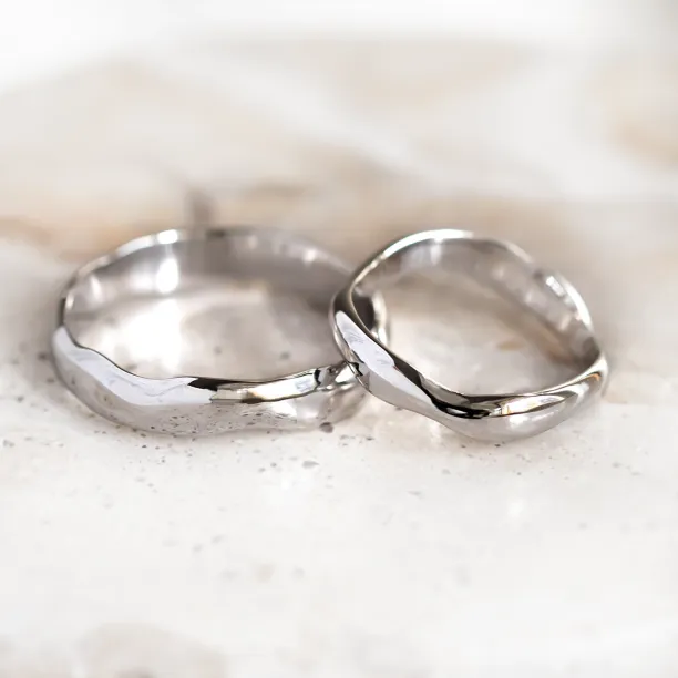 LUANA pair of irregular gold wedding rings shown from a low angle