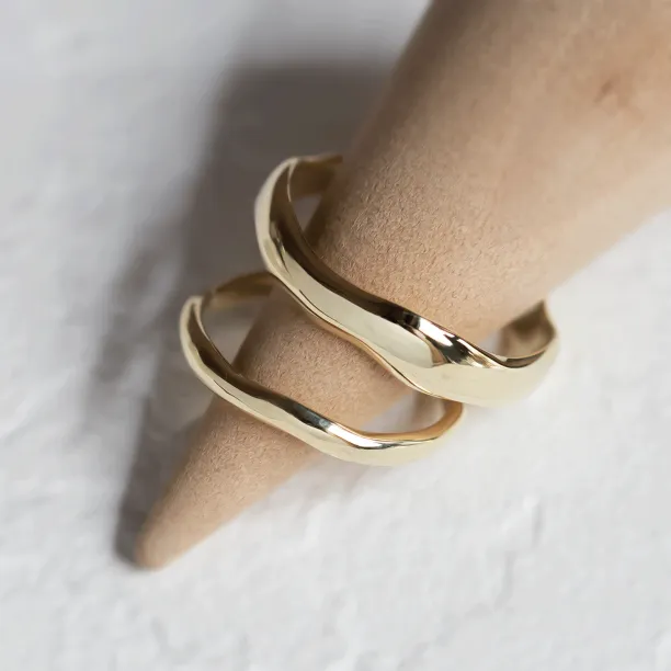 LUANA irregular gold wedding rings displayed together on a ring holder