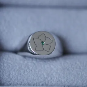 Close-up of the CLARK gold ring's engraved flower and central emerald
