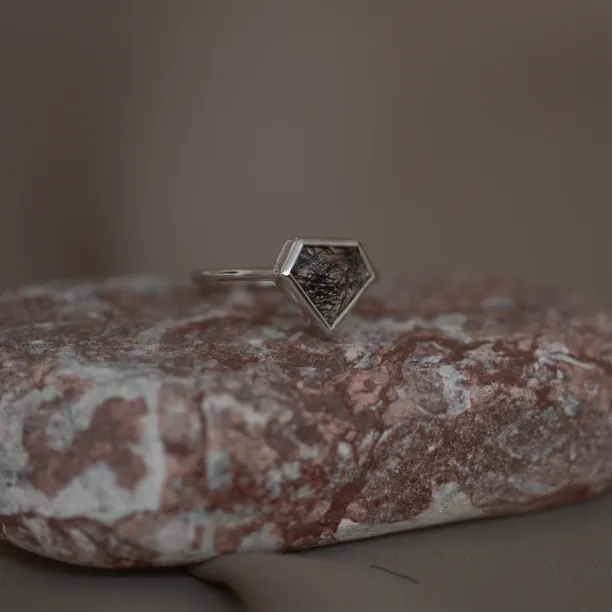 Angled view of the gold ALMONTE ring with rutile quartz on a stone