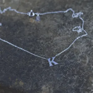 Angled close-up of the VERTE silver letter K diamond pendant
