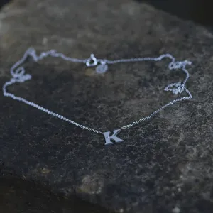 Angled view of the VERTE silver letter K diamond necklace