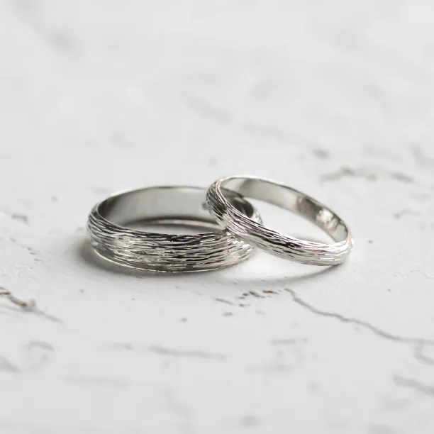 Angled view of DRIS gold wedding rings with textured bands