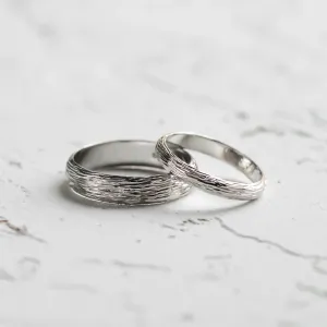 Angled view of DRIS gold wedding rings with textured bands