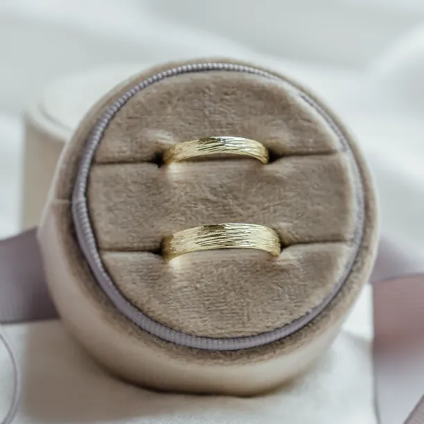 Pair of DRIS gold wedding rings showing the textured band surface