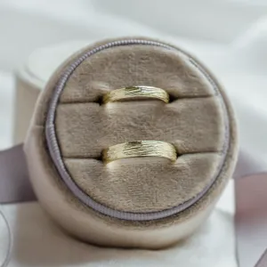 Pair of DRIS gold wedding rings showing the textured band surface
