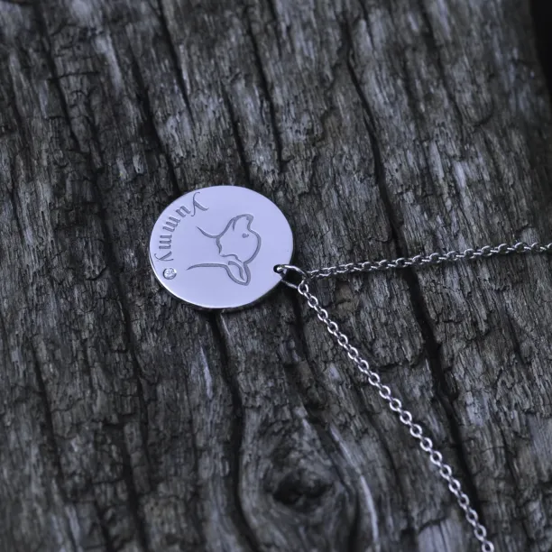 Angled view of the YUM silver pendant with engraved dog portrait