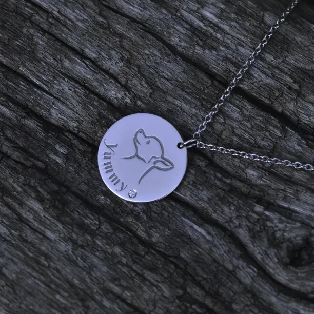 Angled close-up of the YUM silver pendant with dog engraving
