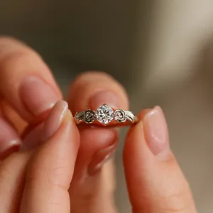 Zásnubní zlatý prsten s moissanitem PENI držený mezi prsty, čelní detail