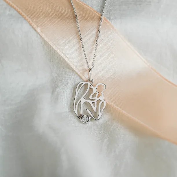 Detailní šikmý pohled na zlatý přívěsek MOMMY s diamantem a siluetou matky s dítětem
