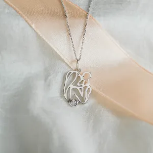 Detailní šikmý pohled na zlatý přívěsek MOMMY s diamantem a siluetou matky s dítětem