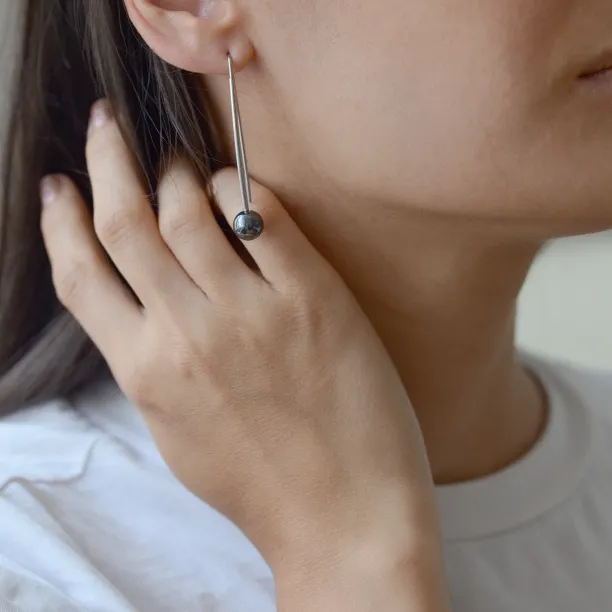 Minimalistická náušnice NUGATA s hematitem nasazená na uchu v detailu