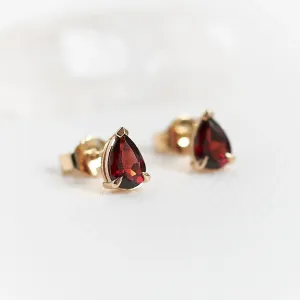 Angled close-up of CARLIE gold earrings with pear-shaped garnets