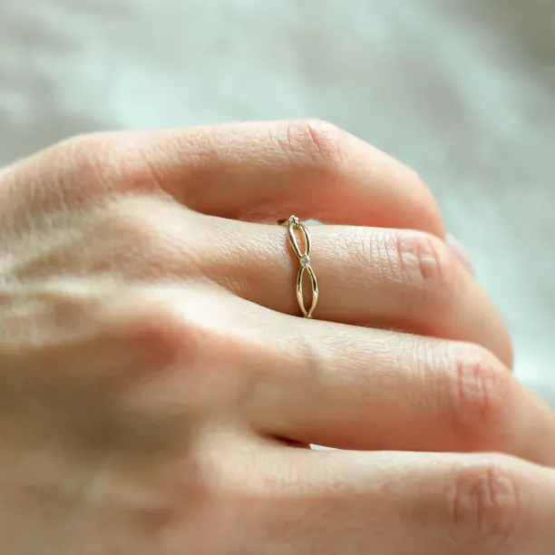 Gold diamond twisted ring worn on a hand