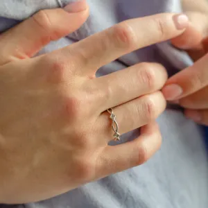 Gold TARANIS ring with interlaced design worn on the hand