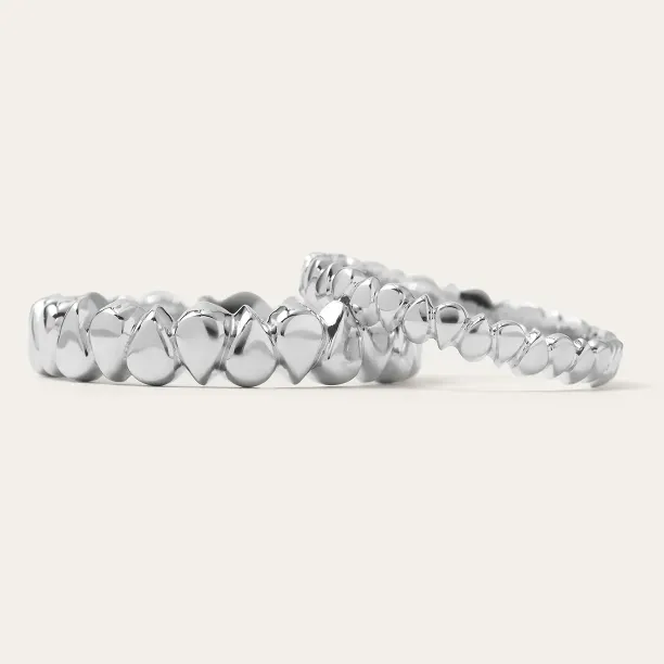Low-angle view of EIRA geometric wedding rings with repeating textured details