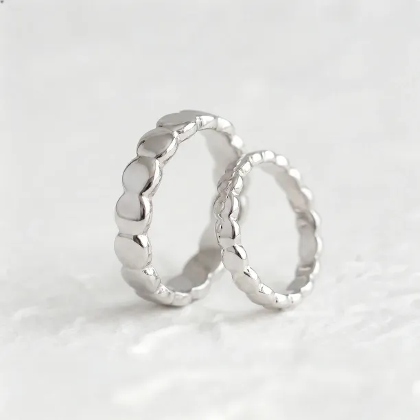 Angled view of matching NOMA geometric wedding rings with organic structure