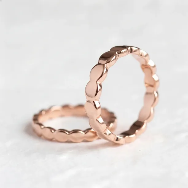 Angled view of matching NOMA geometric wedding rings in 14K rose gold