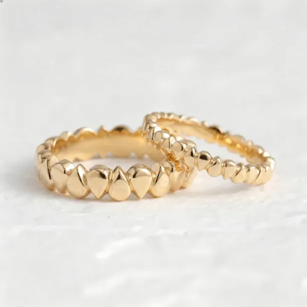 Angled close-up of EIRA geometric wedding rings with rounded textured details