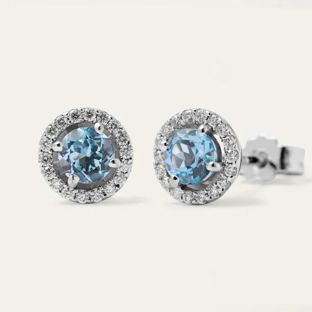 Angled view of DOLLY stud earrings with blue topaz and diamond surrounds