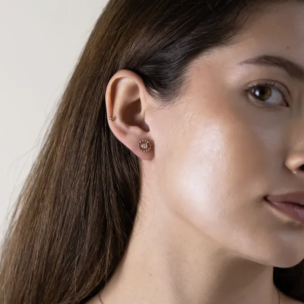 FLOS flower stud earring worn on the ear