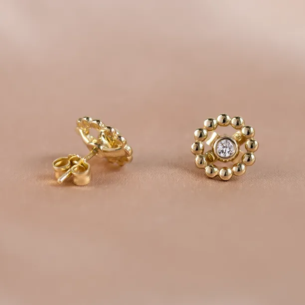 Angled view of FLOS gold earrings with removable gemstone and flower frames
